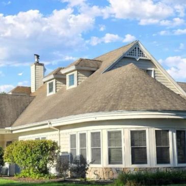 Large house with a complex roof under a partly cloudy sky.