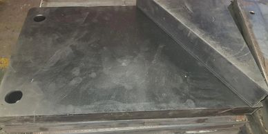 Stack of black rubber sheets with holes, one folded.