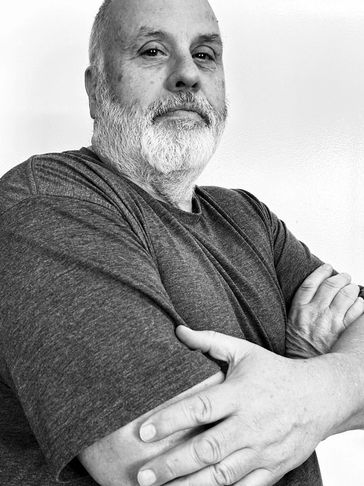 Confident older man with a white beard and folded arms in grayscale.