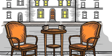 Two seats facing each-other on the street. A coffee table is inbetween with cups of coffee on it.