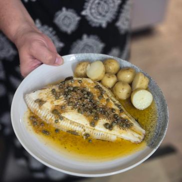 Plate of fish with baby potatoes and sauce.