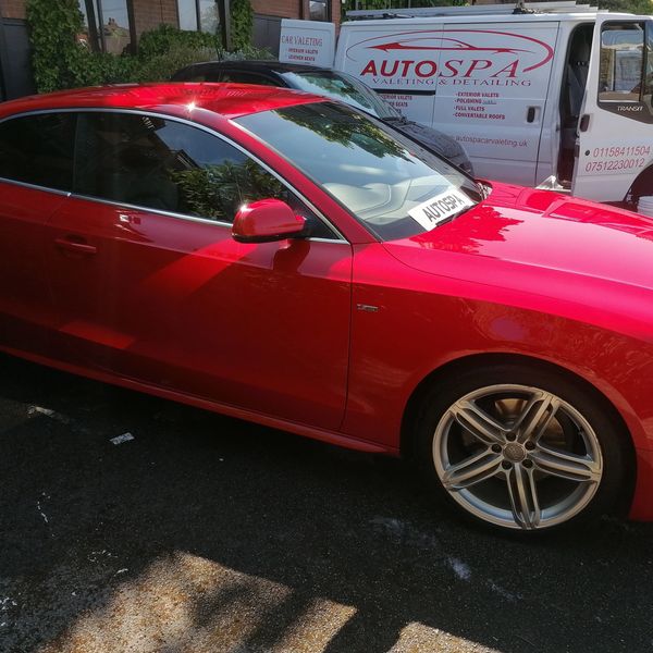 Shiny red Audi parked near an AutoSpa valeting van on a sunny day.