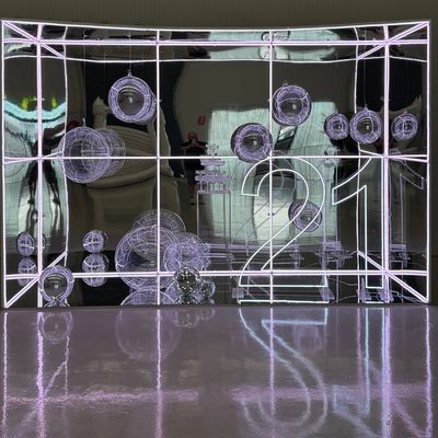Illuminated 3D wireframe spheres and numbers 21 in a reflective display case.