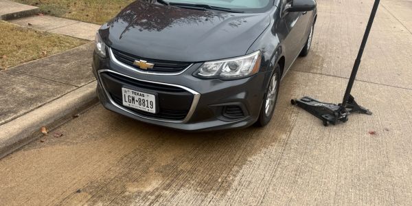 Gray Chevrolet parked on the side with a jack nearby on the road.