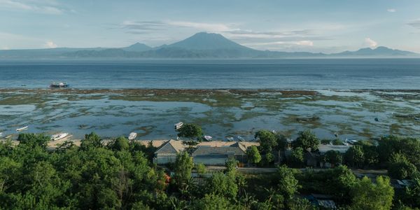 Coastal village with boats and a distant mountain under a clear sky.