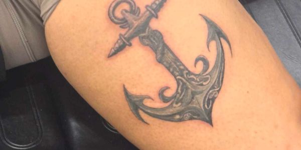 Intricate black and gray anchor tattoo on arm.
