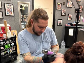Tattoo artist working on a client.