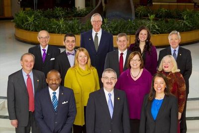 13 trustees standing in front of a plant display smiling for the official 2014 picture