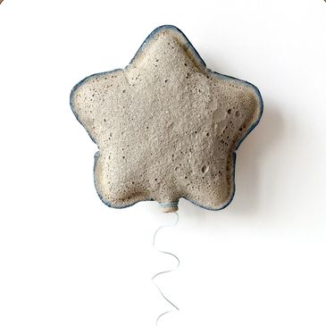Star-shaped ceramic balloon with a delicate string on white background.