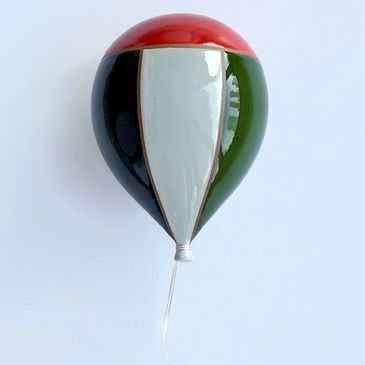 Glossy ceramic balloon with red, black, white, and green colors and a silver string.