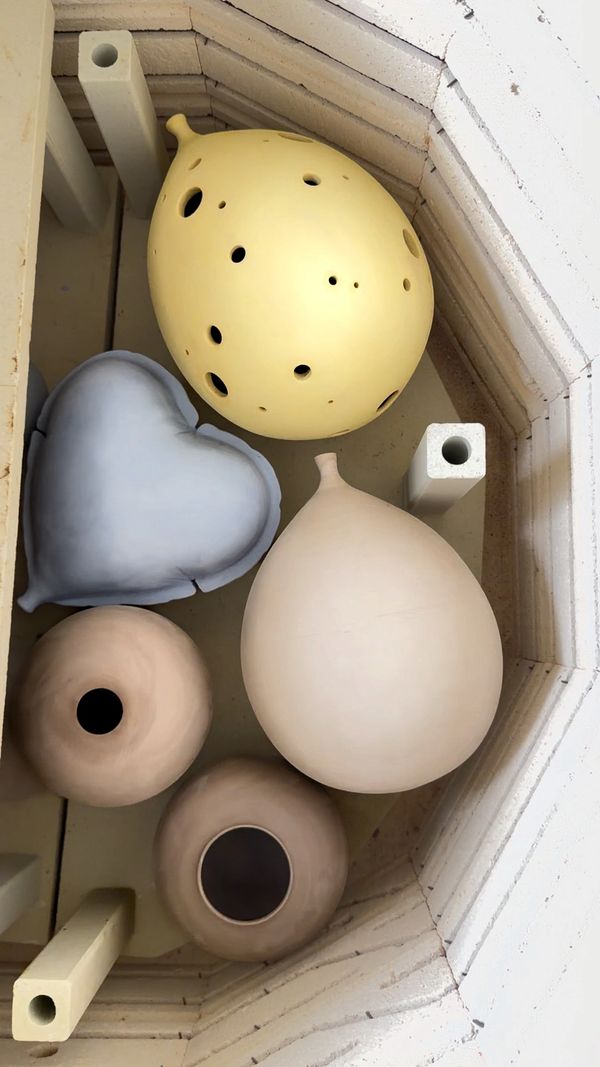Five ceramic vessels with different shapes inside a kiln.