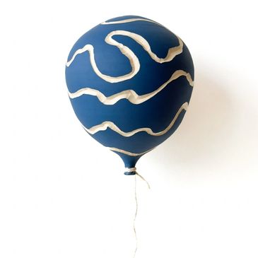 Blue balloon with white abstract patterns on a beige background.