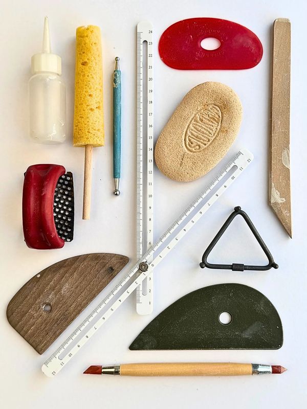 A collection of pottery and sculpting tools arranged neatly on a white surface.