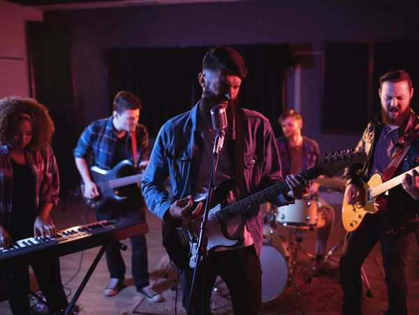 A passionate band performing intensely in a dimly lit studio.