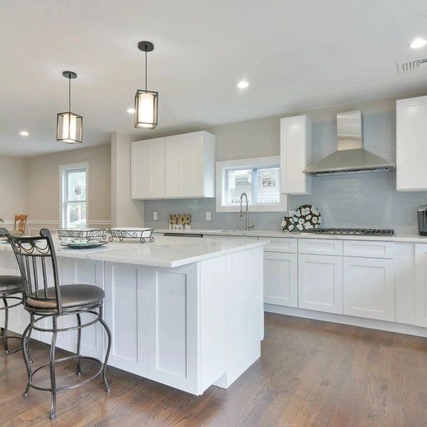 Bright modern kitchen with white cabinets and wooden floors.