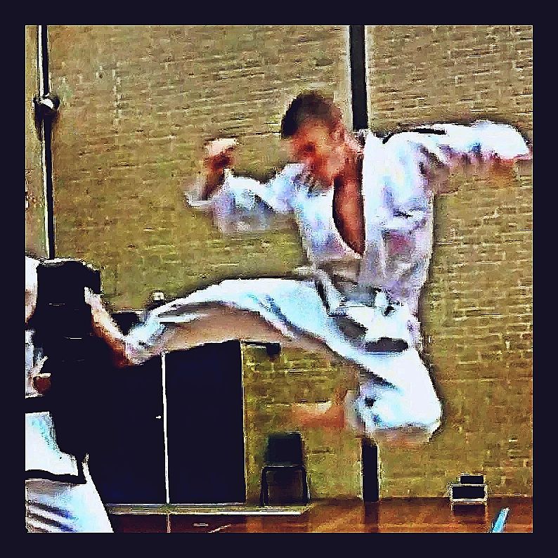 Martial artist performing a high flying kick indoors.