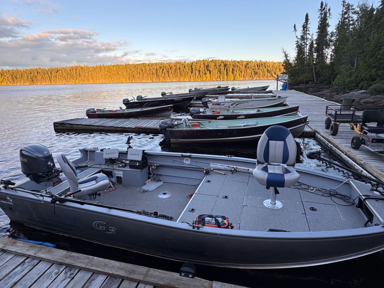 Fishing boats docked at a serene lake with sunset lighting.