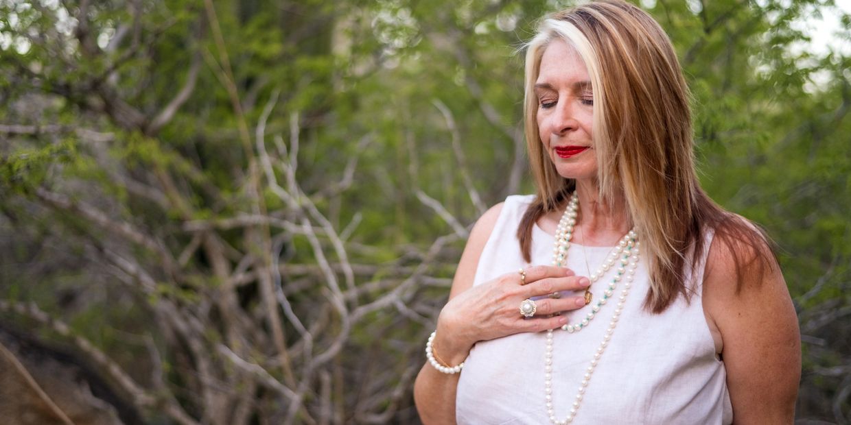 Woman smiling with eyes closed and hand on heart.