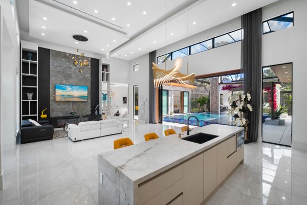 Modern open-concept living area with sleek kitchen and pool view.