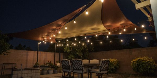 Sail Shades, with cafe style lighting, over an outdoor dining area