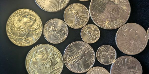 A collection of various gold coins on a black surface.