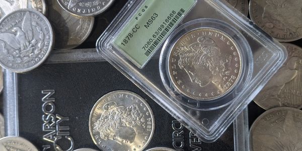 Collection of silver coins including an 1878-CC Morgan dollar graded MS63.