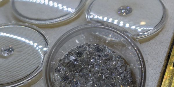 Close-up of loose diamonds in containers on a fabric surface.