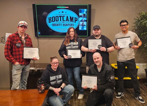 Group of six people proudly holding Bootcamp for Bounty Hunters certificates.