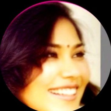 Close-up of a smiling woman with dark hair and a small bindi on her forehead.