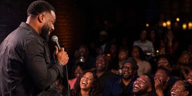 Comedian performing to a laughing audience.