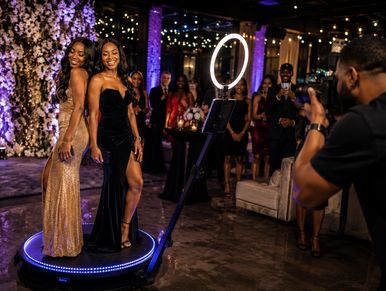 Two women posing on a rotating photo booth platform.
