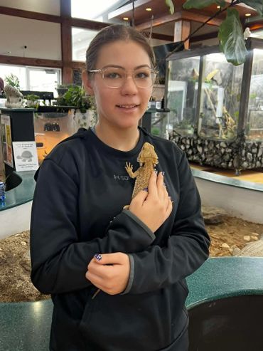 A woman holding a bearded dragon lizard indoors.
