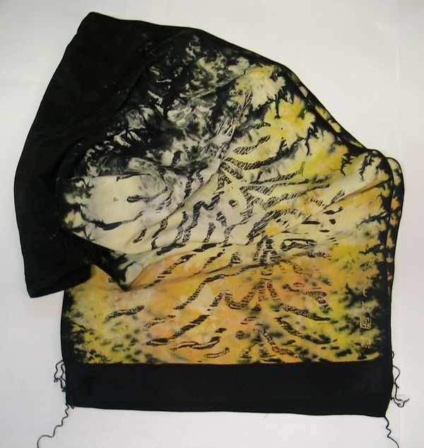A silk scarf that is yellow with black tiger-looking stripes and a black trim