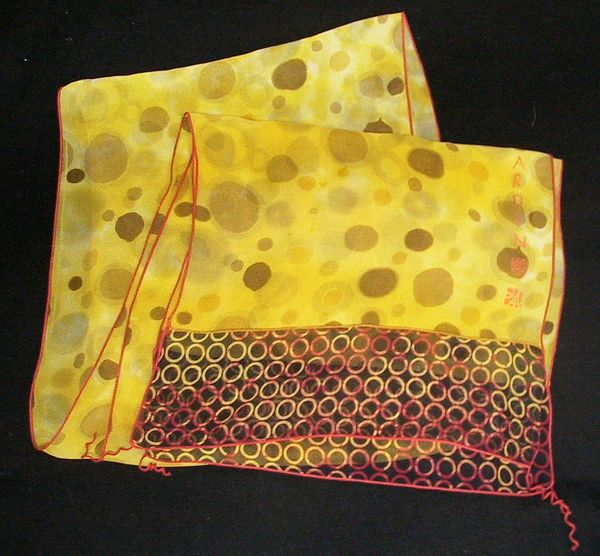 A vibrant yellow silk scarf with sheer brown spots and a circle pattern trim.