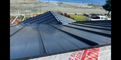 Newly installed black metal roof panels by the beach.