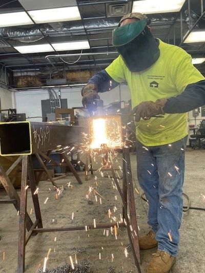 Worker welding metal with sparks flying in workshop.