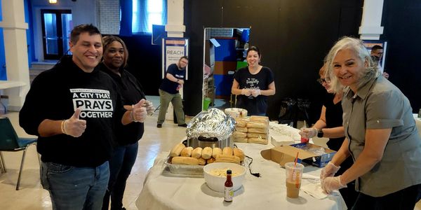 Volunteers prepare and serve food at a community event with smiles and teamwork.