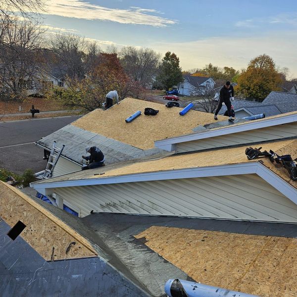 Workers installing new roofing plywood on a house.