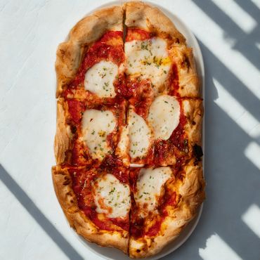 Rectangular pizza with tomato sauce and melted cheese on a white plate.