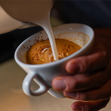 Cream being poured into a cup of coffee.