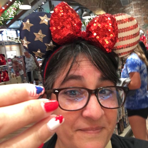 Woman wearing patriotic Mickey ears and matching red, white, and blue nails.