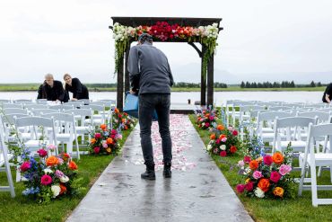 Person preparing floral aisle for outdoor wedding.