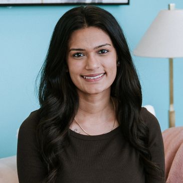 Smiling woman with long dark hair indoors.