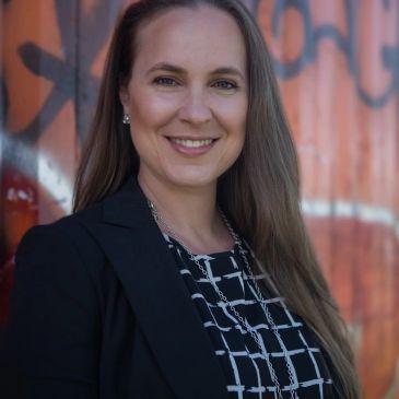 Smiling woman in blazer with long hair.