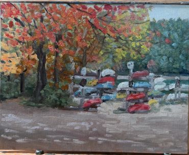 Autumn scene with colorful trees and stacked boats.