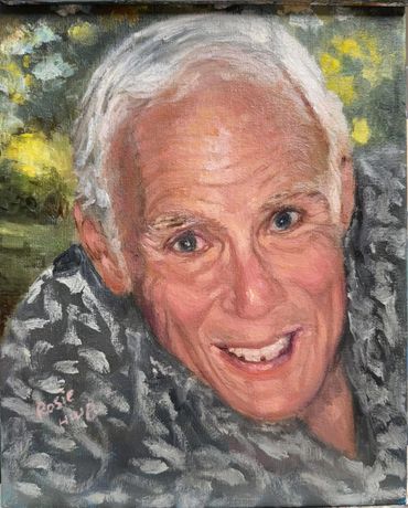 A smiling elderly man in a patterned shirt.