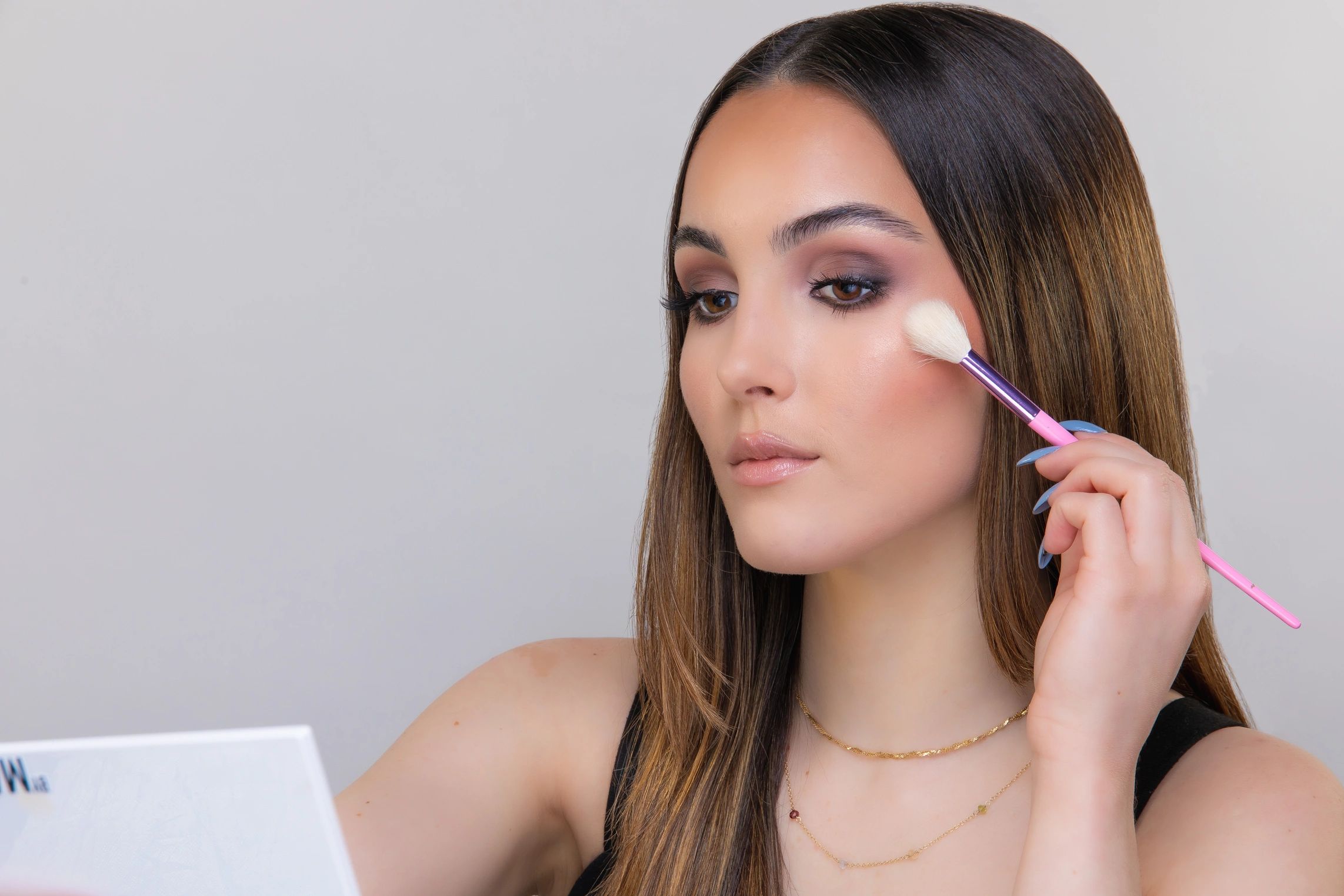 Woman applying makeup with a brush on her cheek.