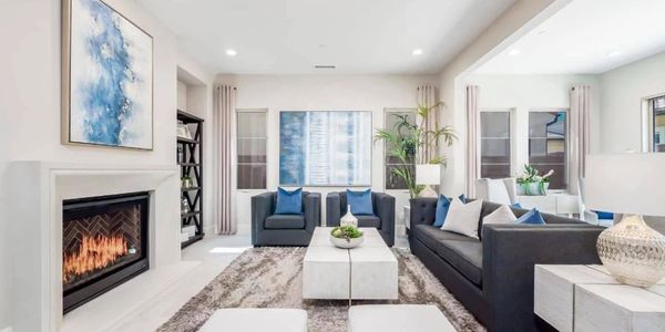 Modern living room with gray furniture, blue accents, and a cozy fireplace.