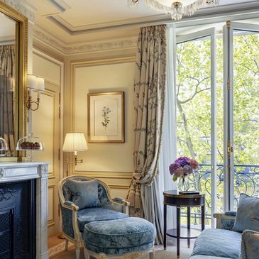 Elegant living room with classic blue furniture and large windows overlooking greenery.