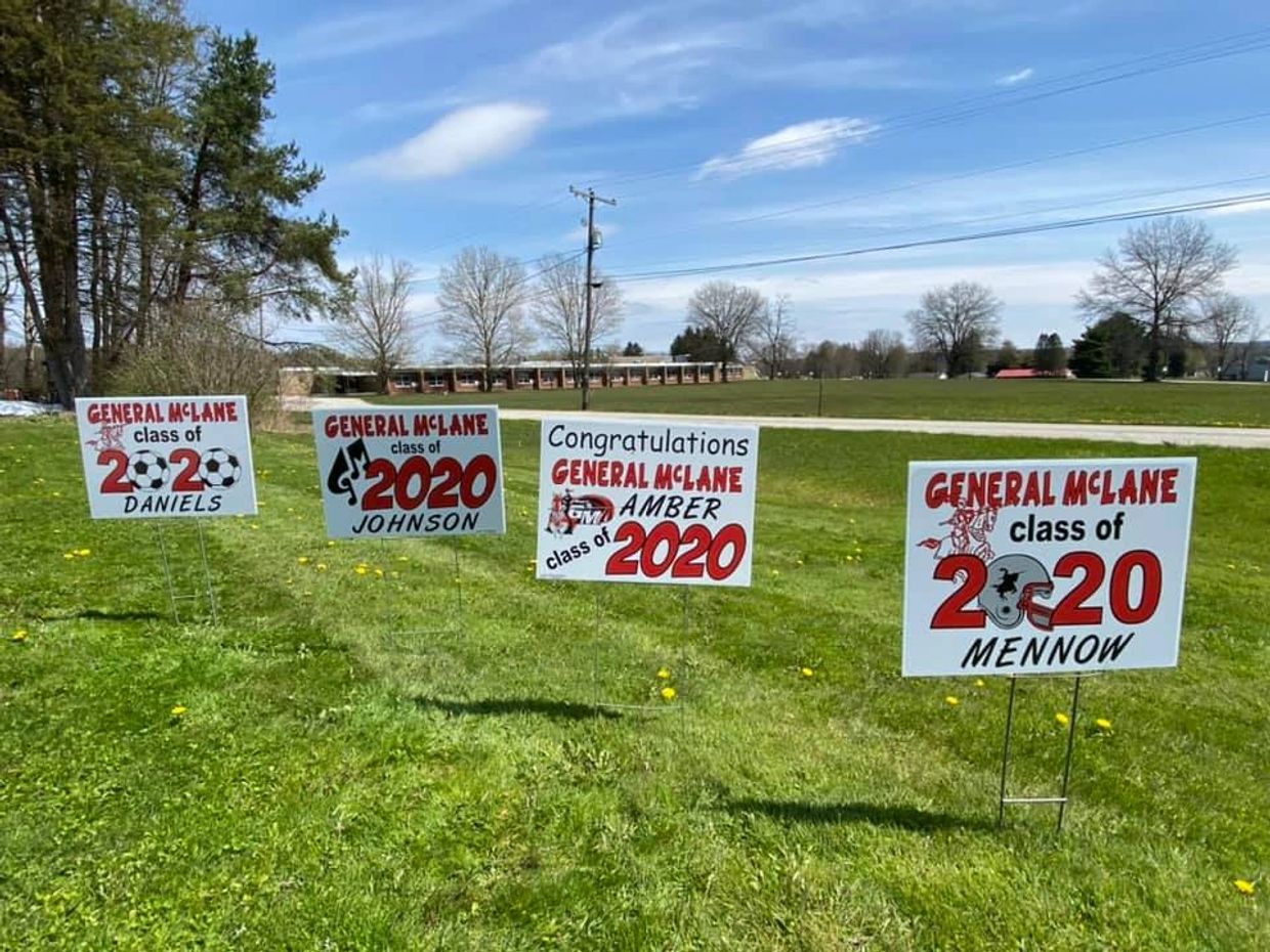 Several white rectangular signs with red and black writing in grassy field